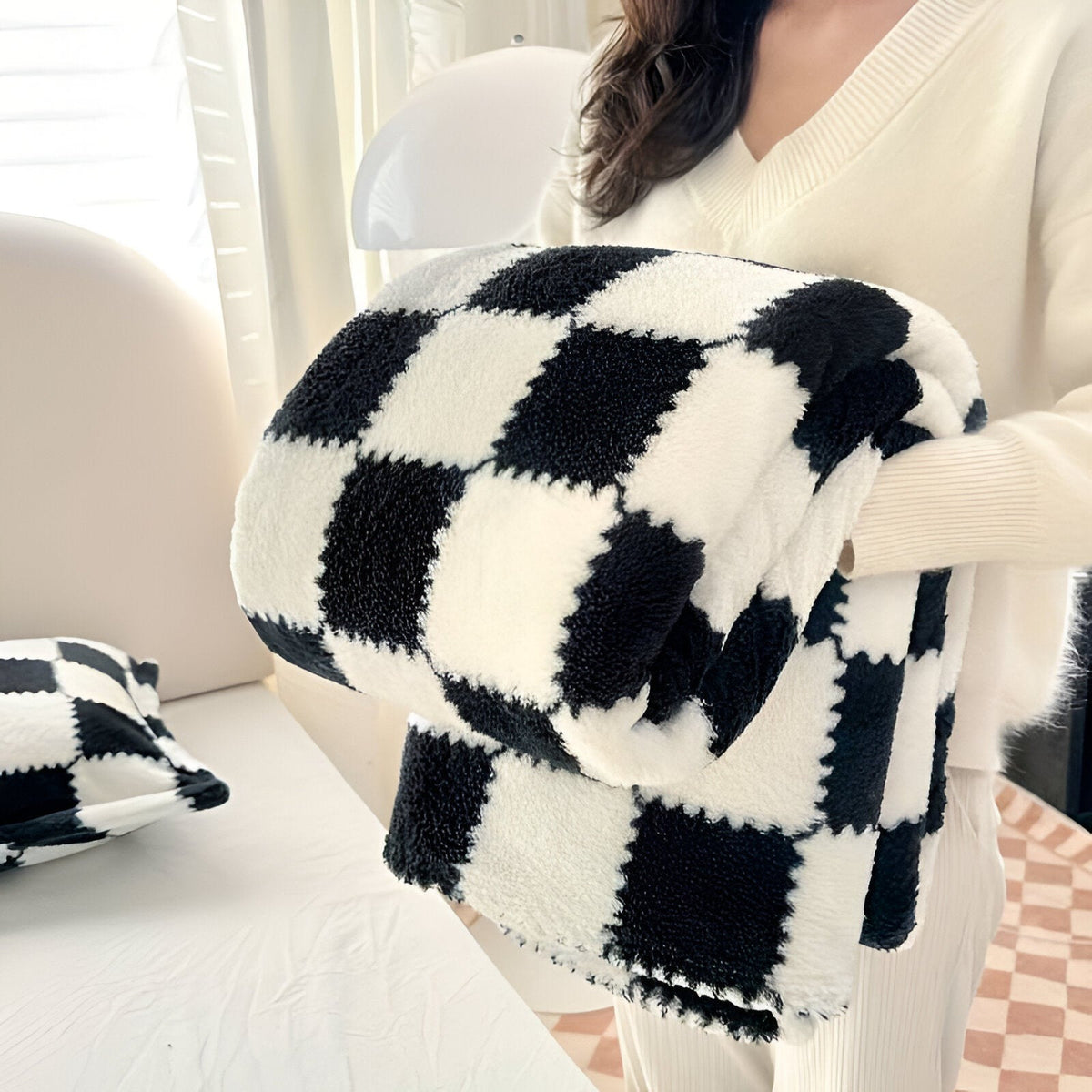 Teddy fleece blanket with a checkerboard pattern, folded in someone's arms - black