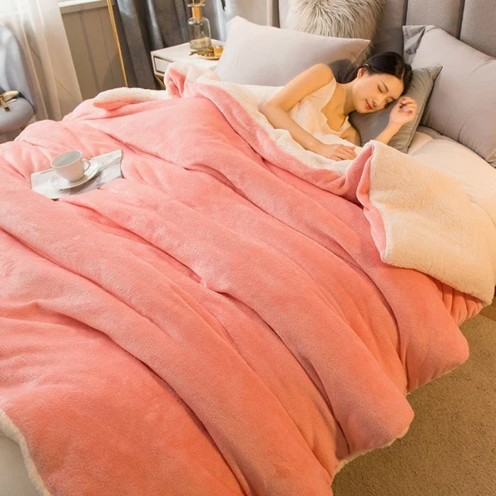 Thick sherpa blanket with a velvet-soft side on a bed - salmon pink