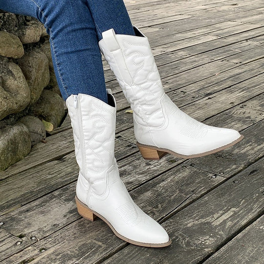 White women's cowboy boots with western stitching, worn with jeans
