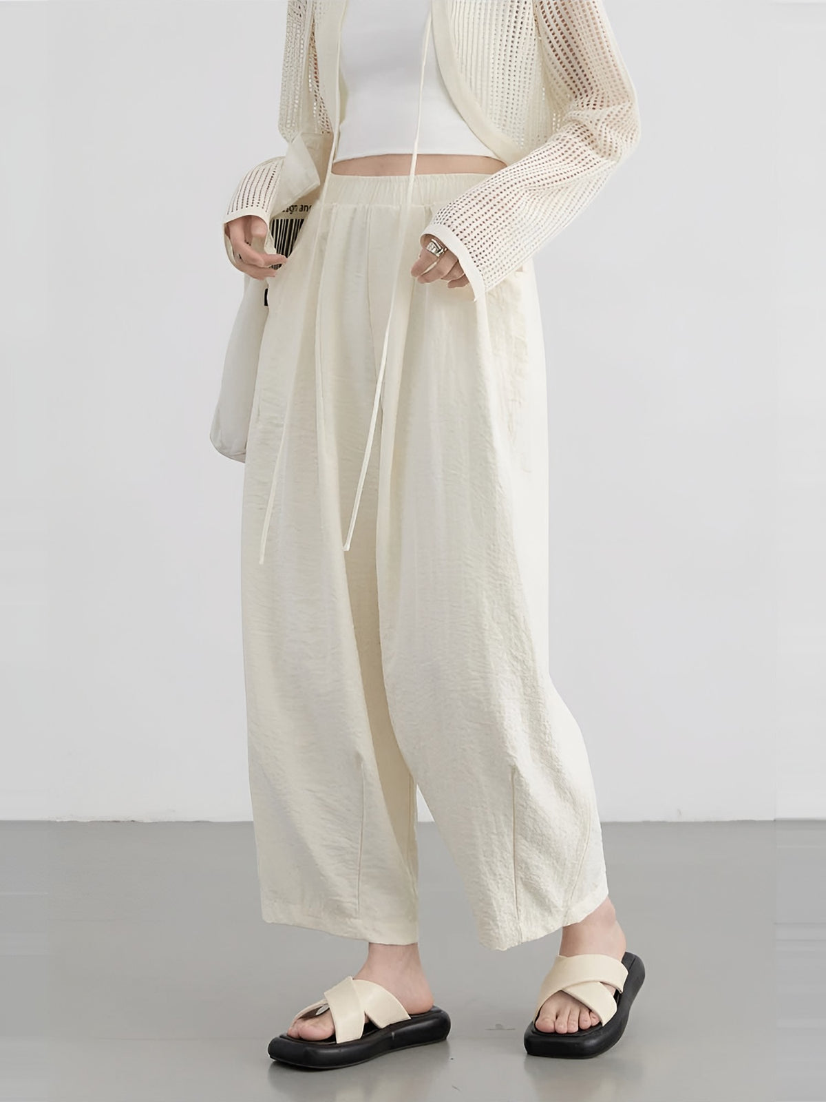 Women's cream wide-leg trousers with pleats, worn with an open cardigan