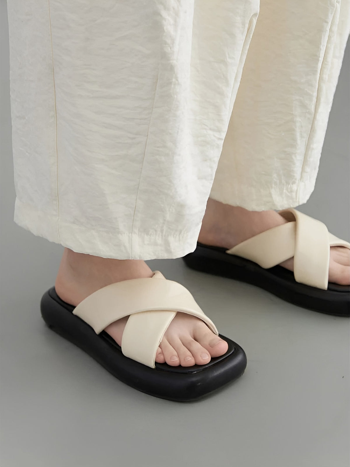 Close-up of the ankle-length hem of the cream trousers