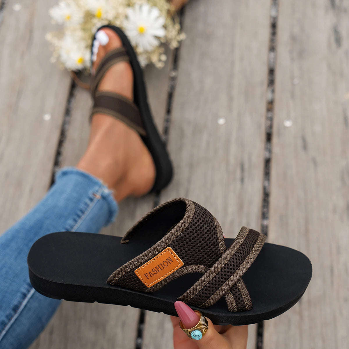 Sliders with crossed mesh straps, a small label and a flat black sole