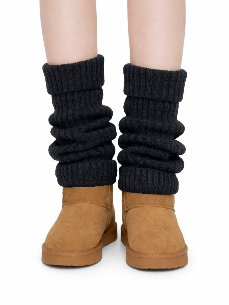 Women's ribbed knit leg warmers with a fold-over cuff, worn over boots - black