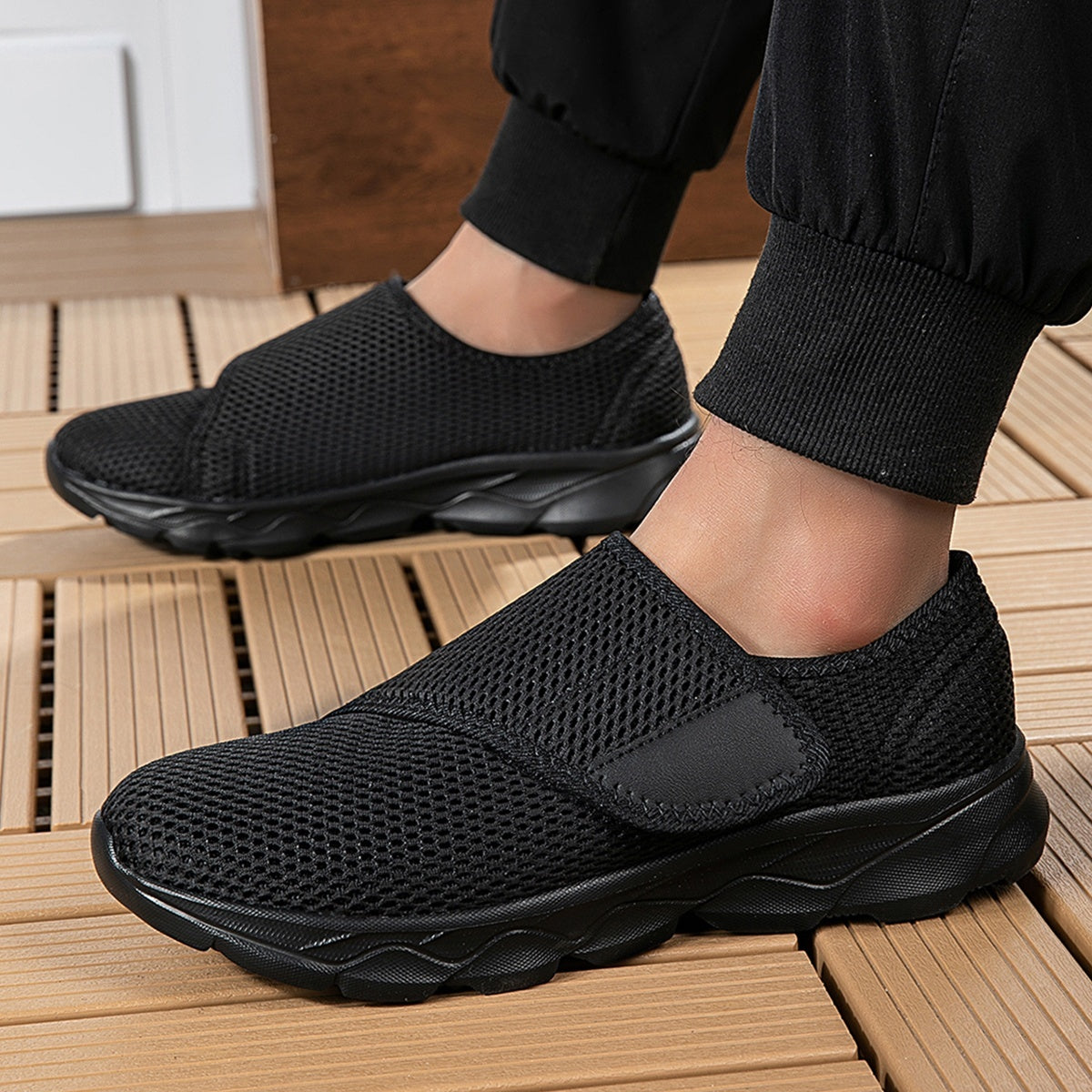 Wide fit mesh shoes for women with broad hook and loop strap over the instep and flat tread sole - black