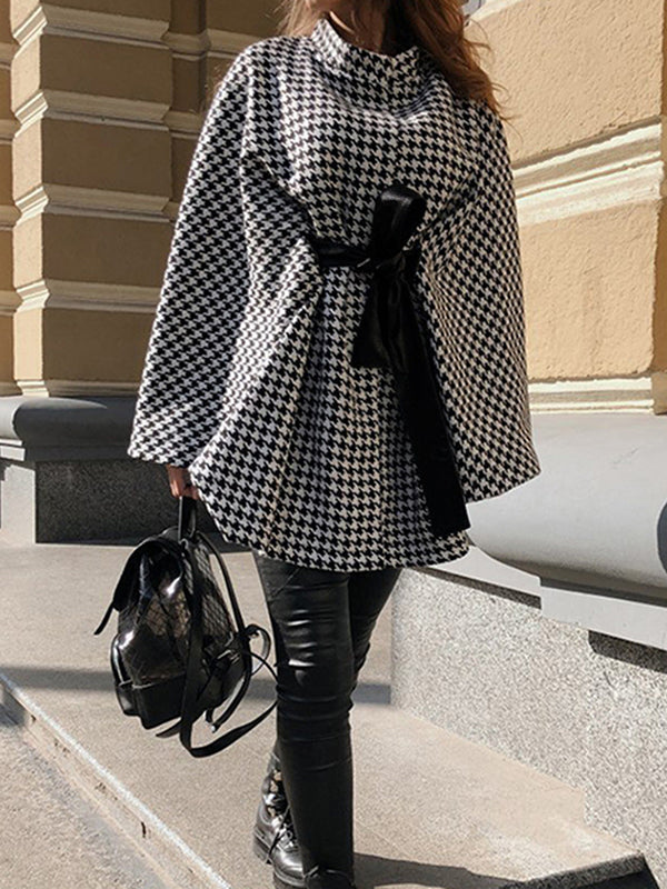 Black and white houndstooth cape coat with a stand collar and tie belt