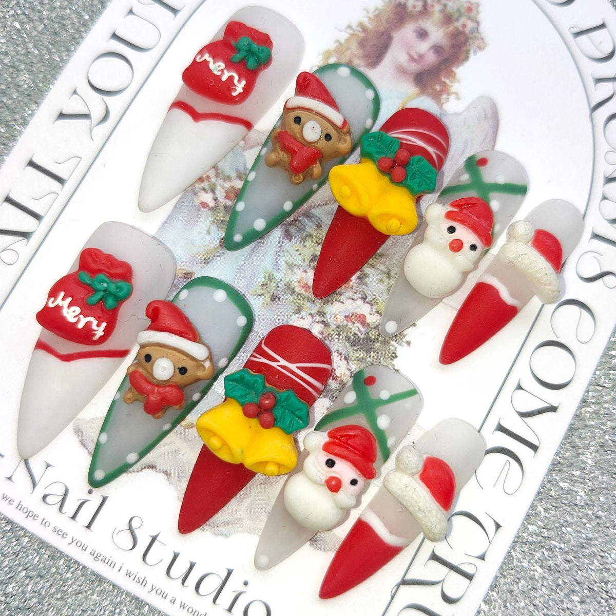 3D Christmas press-on nails with festive figures and bows on a display card