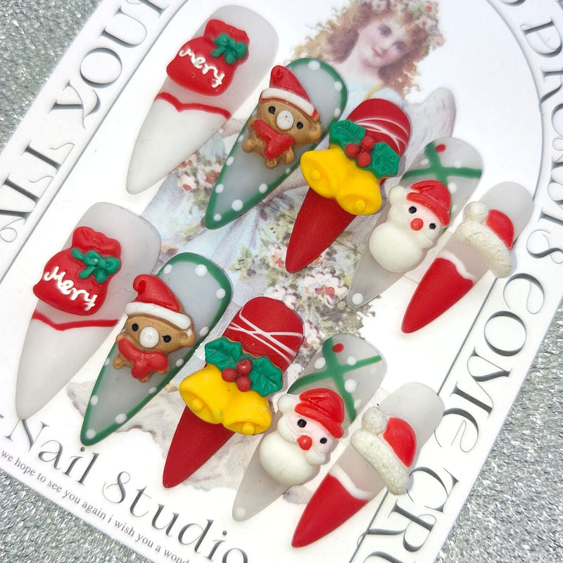 3D Christmas press-on nails with festive figures and bows on a display card