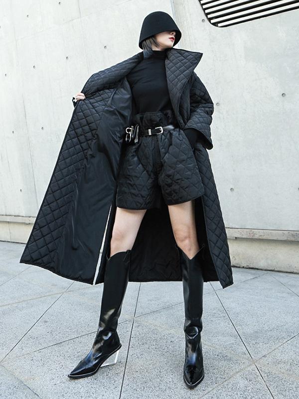 Long black quilted wrap coat with a fold-over collar and ring-buckle belt