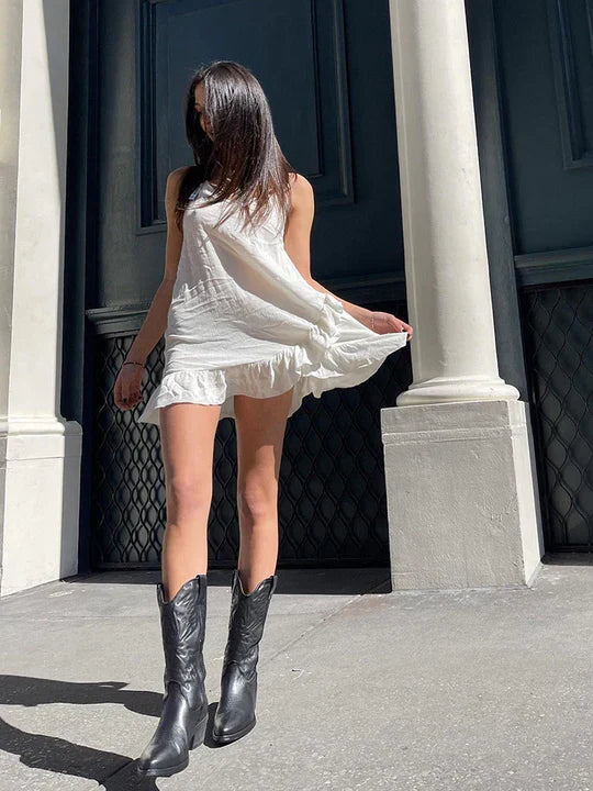 Black cowboy boots worn with a white mini dress