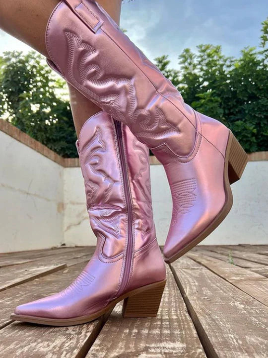 Pink metallic cowboy boots worn outdoors, side view with block heel