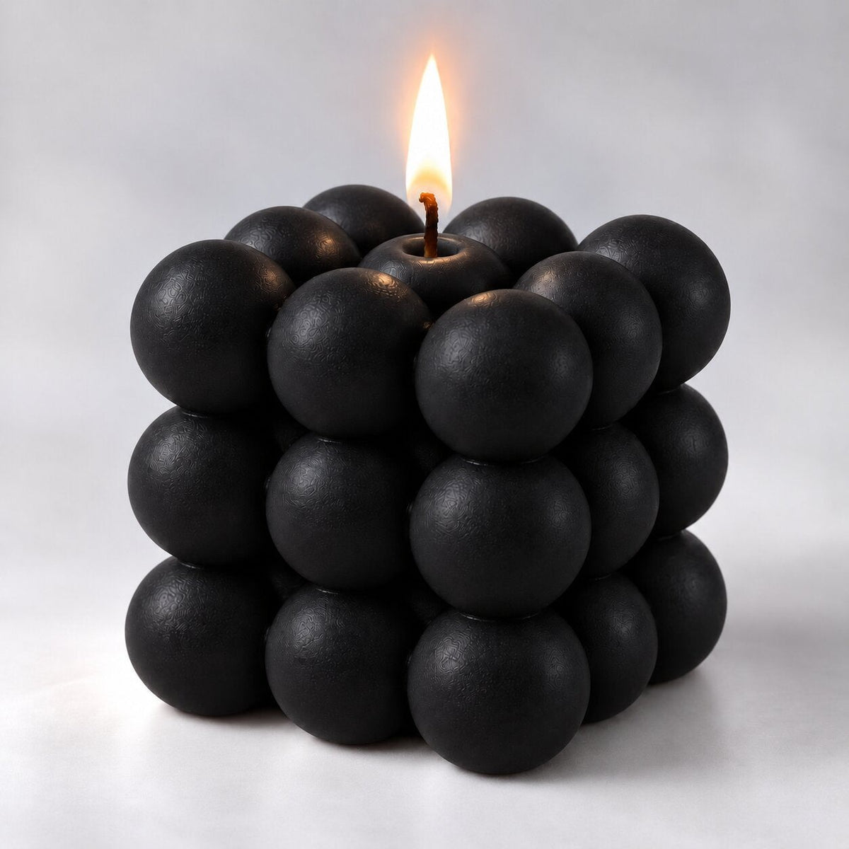 Bubble cube candle with a lit wick - black