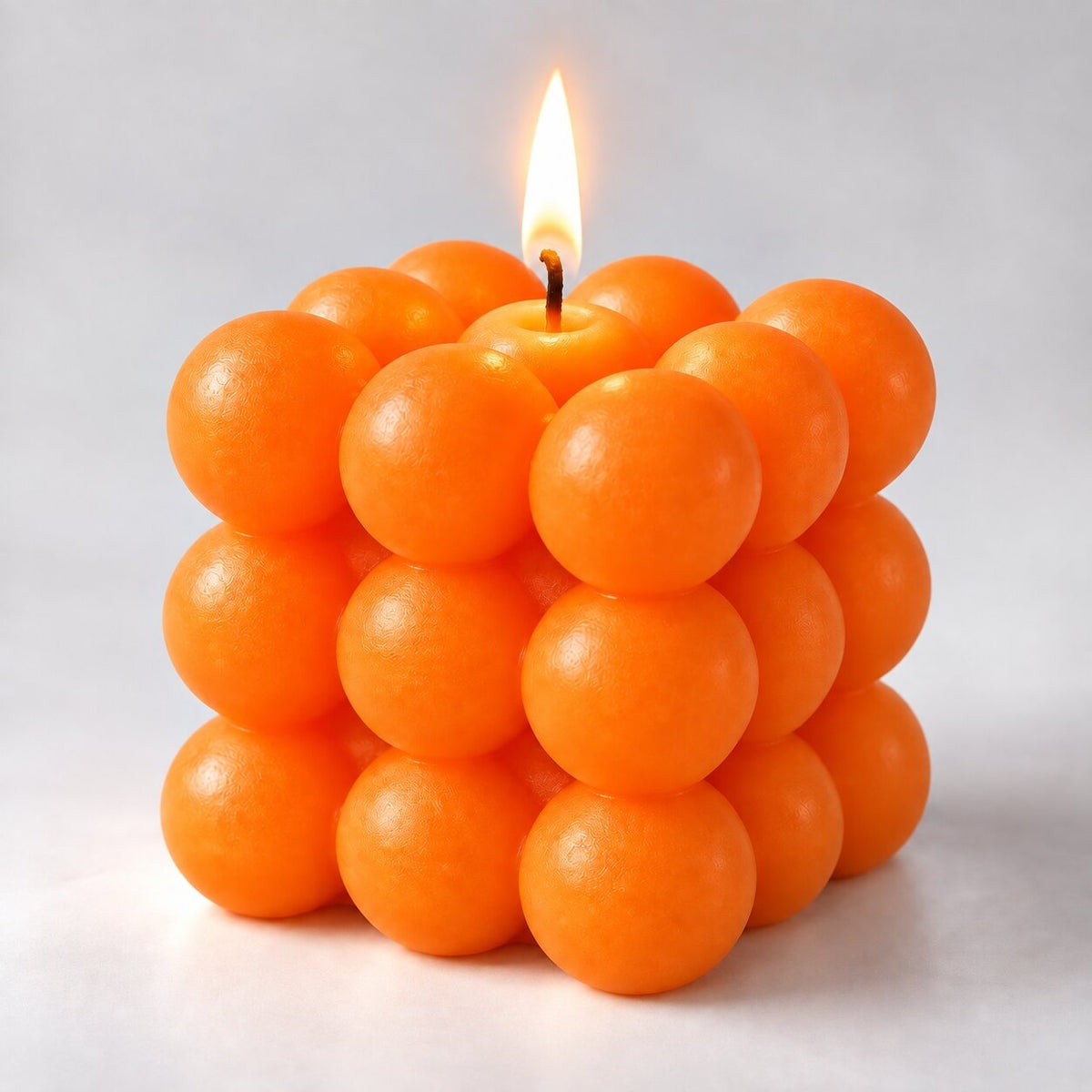 Bubble cube candle with a lit wick - orange