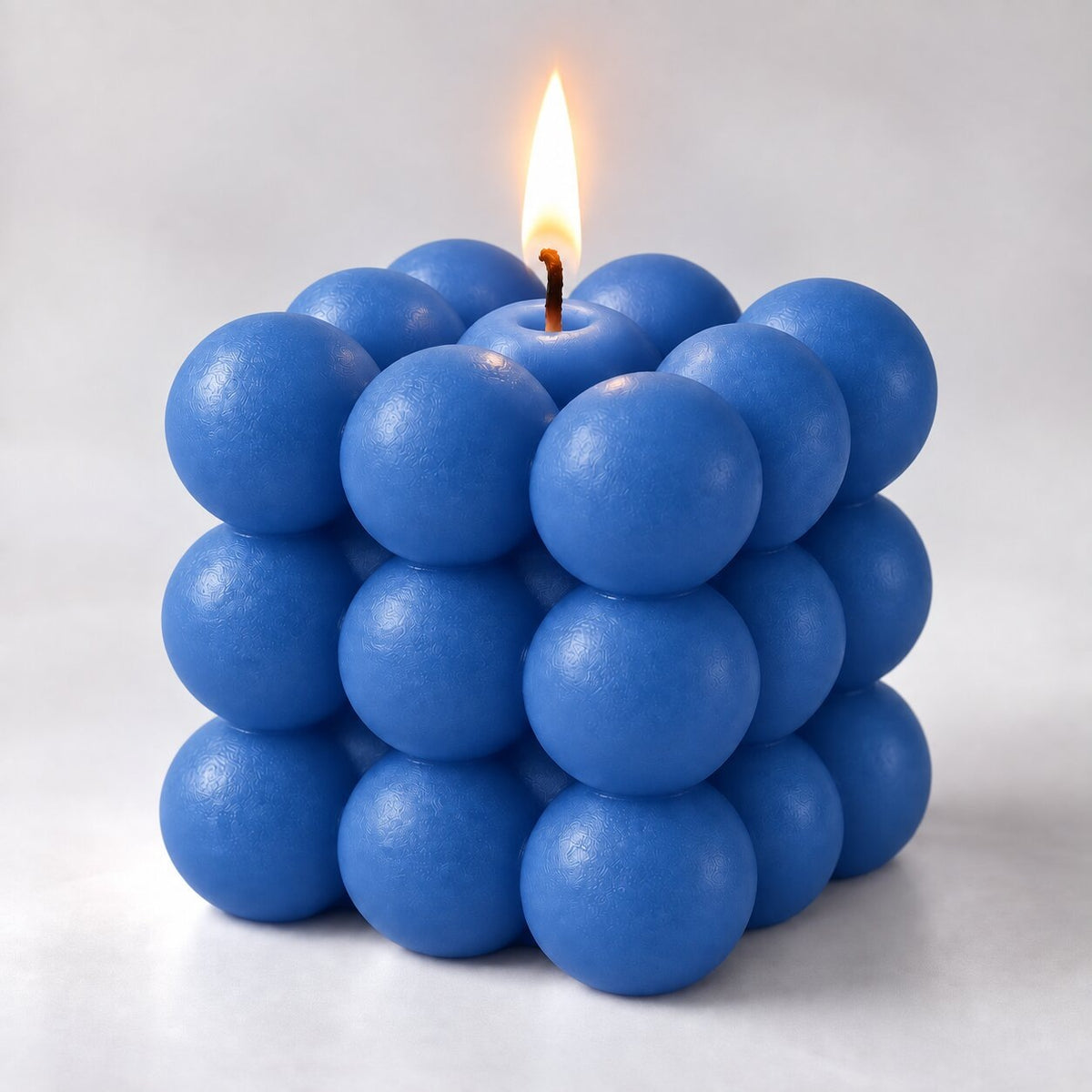 Bubble cube candle with a lit wick - blue