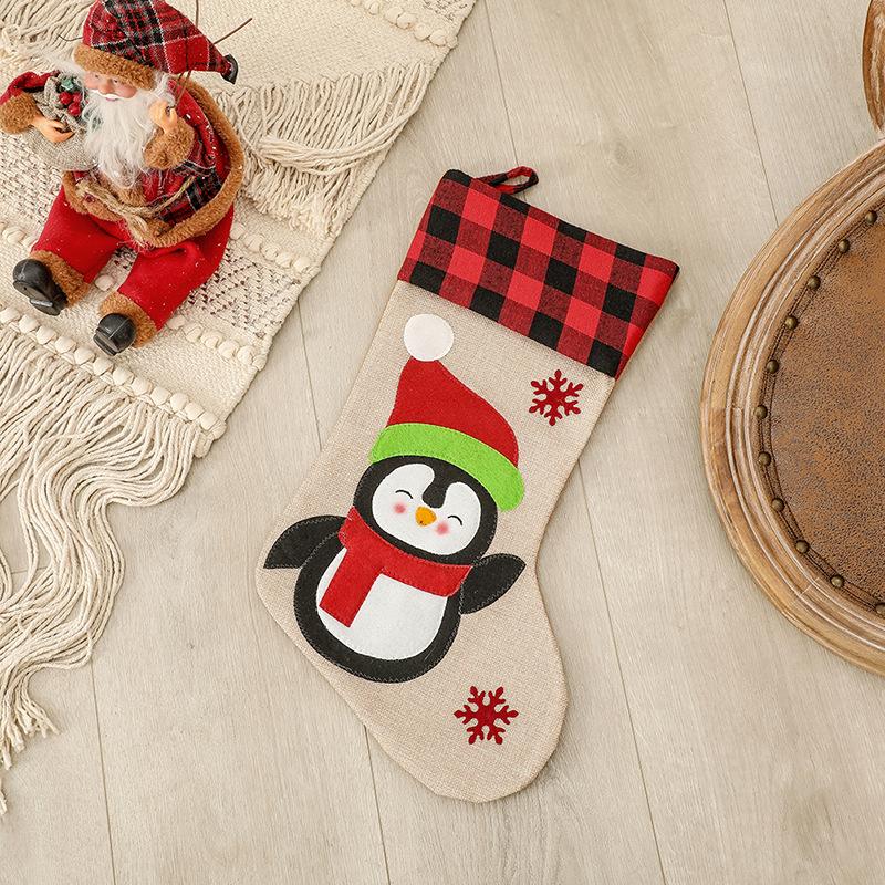Burlap-look Christmas stocking with a red and black check cuff and a character - penguin