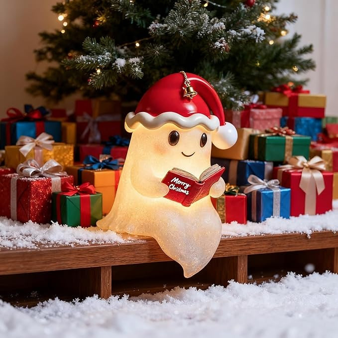 White ghost lamp in a red Santa hat with a bell, holding a red book and glowing warm yellow