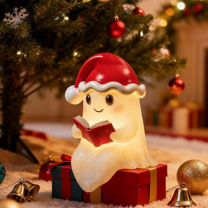White ghost lamp in a red Santa hat with a bell, holding a red book and glowing warm yellow