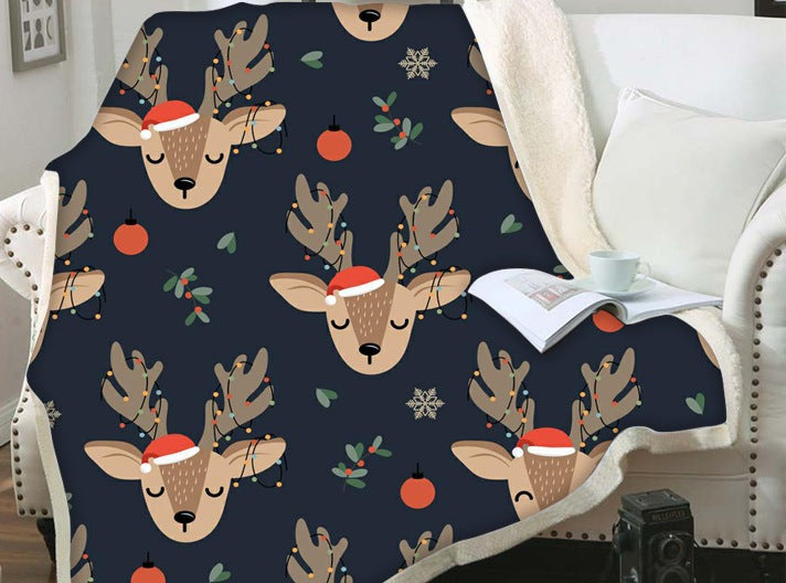 Christmas blanket with a teddy reverse and festive print, over an armchair - navy reindeer faces