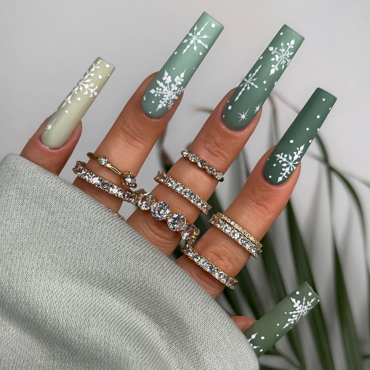 Christmas press-on nails with a festive print, applied on a hand - green snowflakes