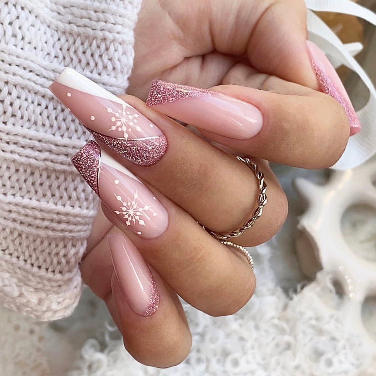 Christmas press-on nails with a festive print, applied on a hand - pink glitter snowflake