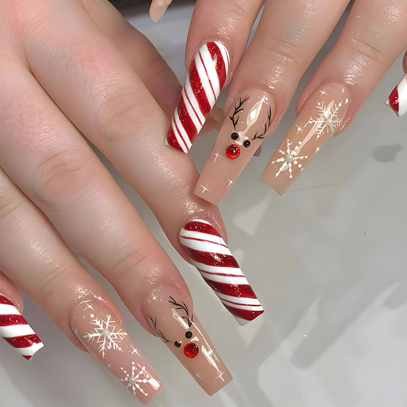 Christmas press-on nails with a festive print, applied on a hand - candy cane with reindeer