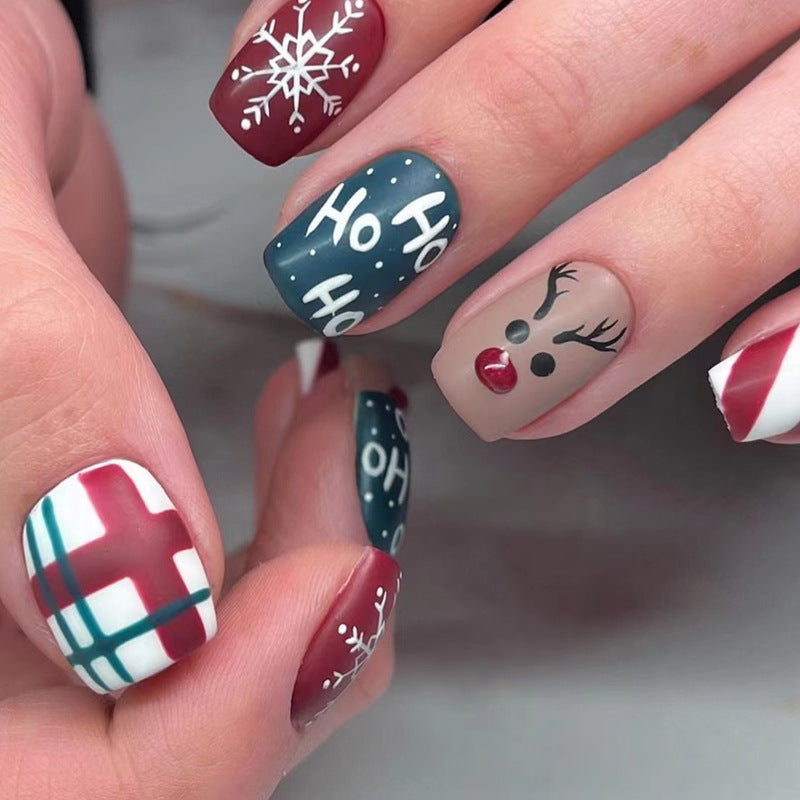 Christmas press-on nails with a festive print, applied on a hand - ho ho ho with reindeer and check