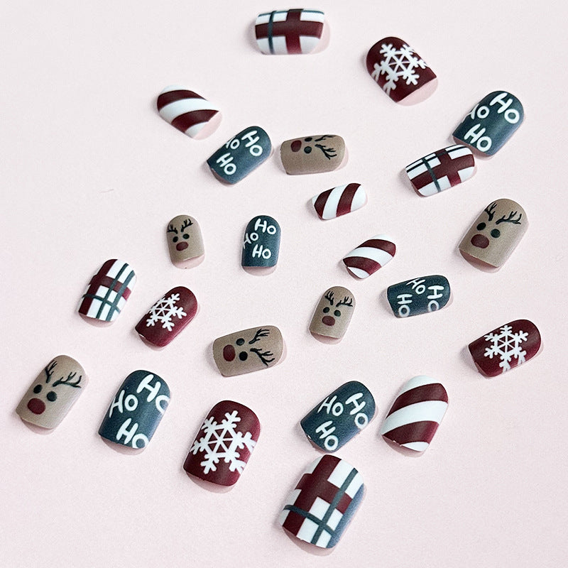 Christmas press-on nails with a festive print, applied on a hand