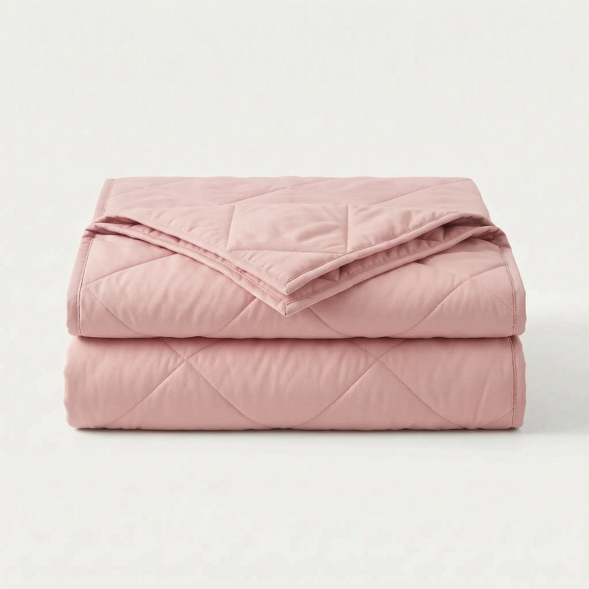 Light cooling blanket with diamond stitching over a made bed - pink