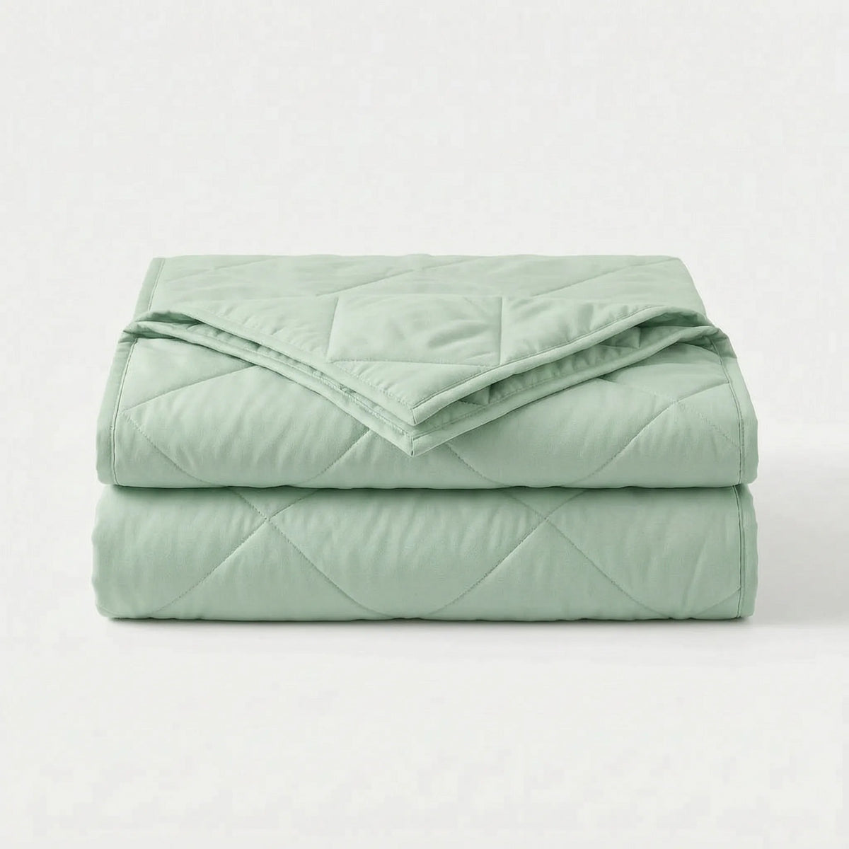 Light cooling blanket with diamond stitching over a made bed - mint green