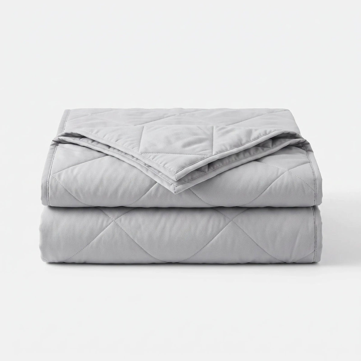 Light cooling blanket with diamond stitching over a made bed - light grey