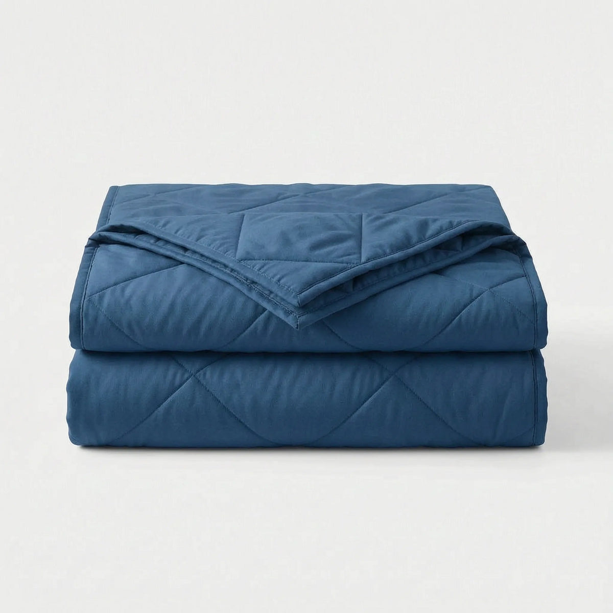 Light cooling blanket with diamond stitching over a made bed - dark blue