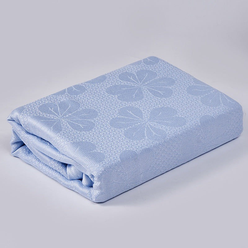 Cooling blanket with a woven floral pattern on a bed - light blue
