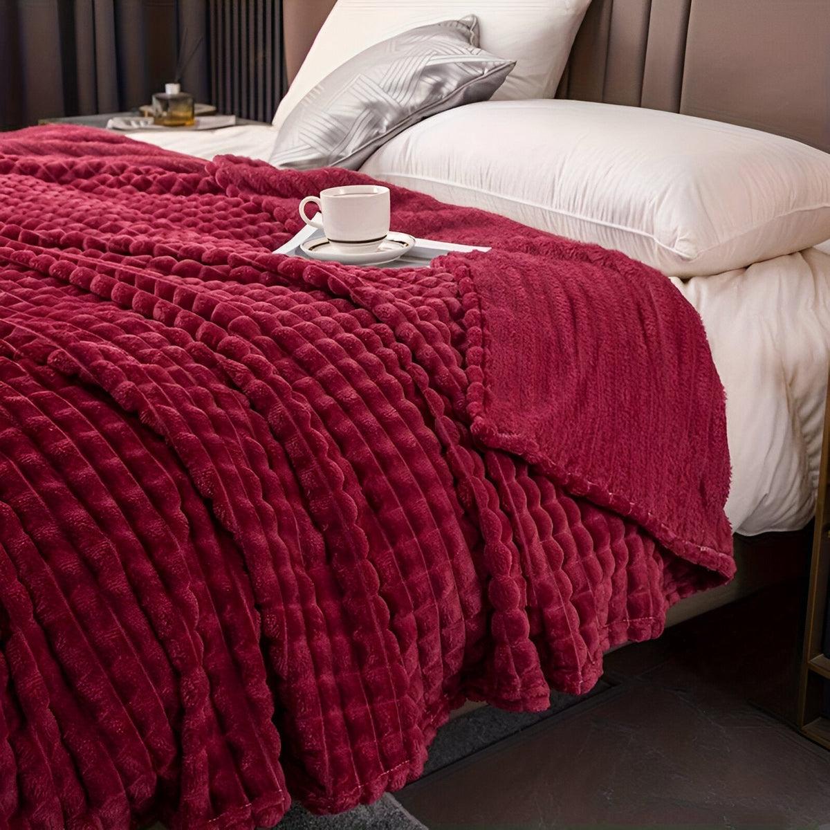 Coral fleece blanket with a square grid texture over a bed - burgundy