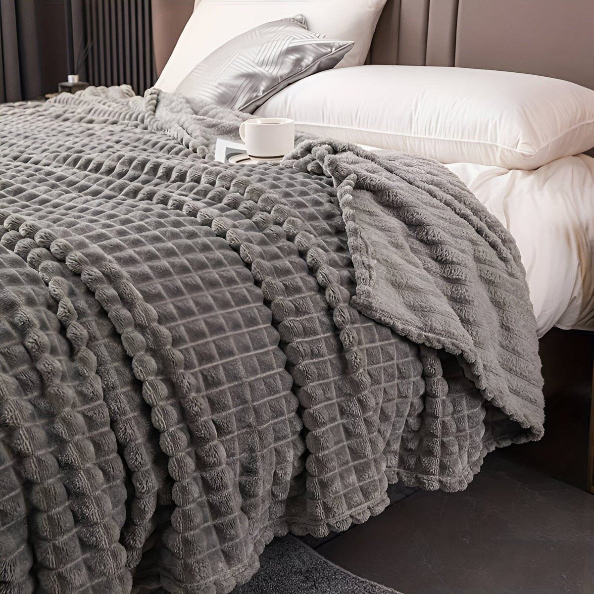 Coral fleece blanket with a square grid texture over a bed - dark grey