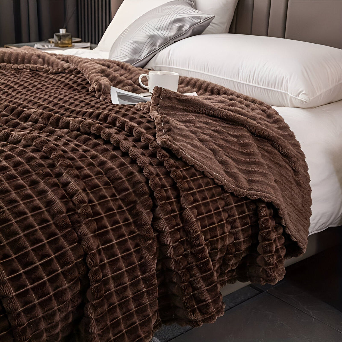 Coral fleece blanket with a square grid texture over a bed - chocolate brown