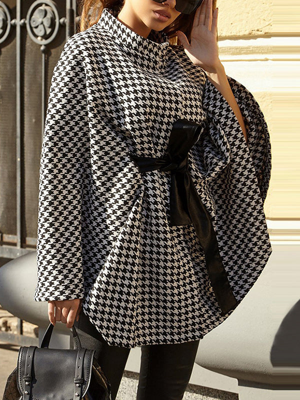 Black and white houndstooth cape coat with a stand collar and tie belt