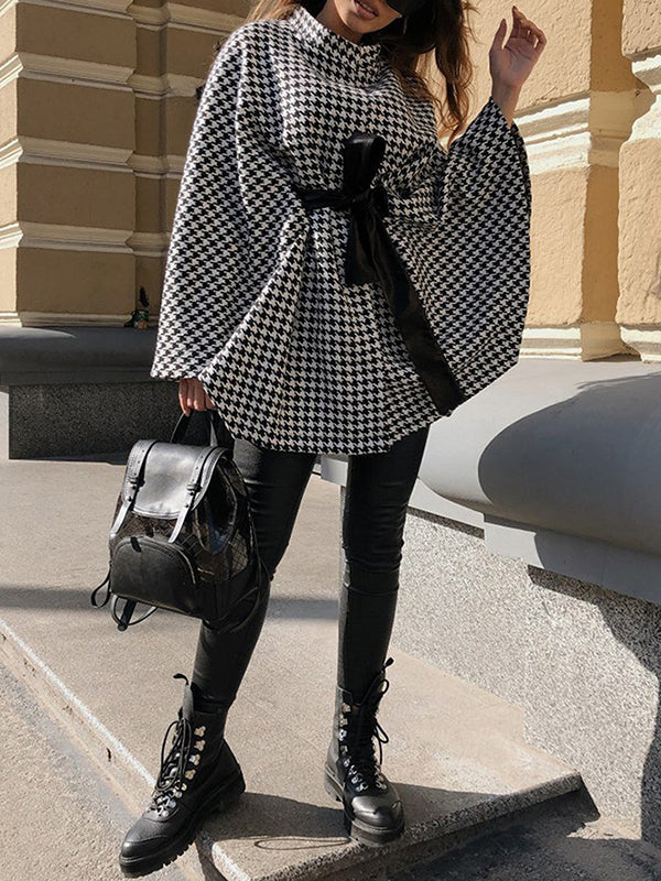 Black and white houndstooth cape coat with a stand collar and tie belt