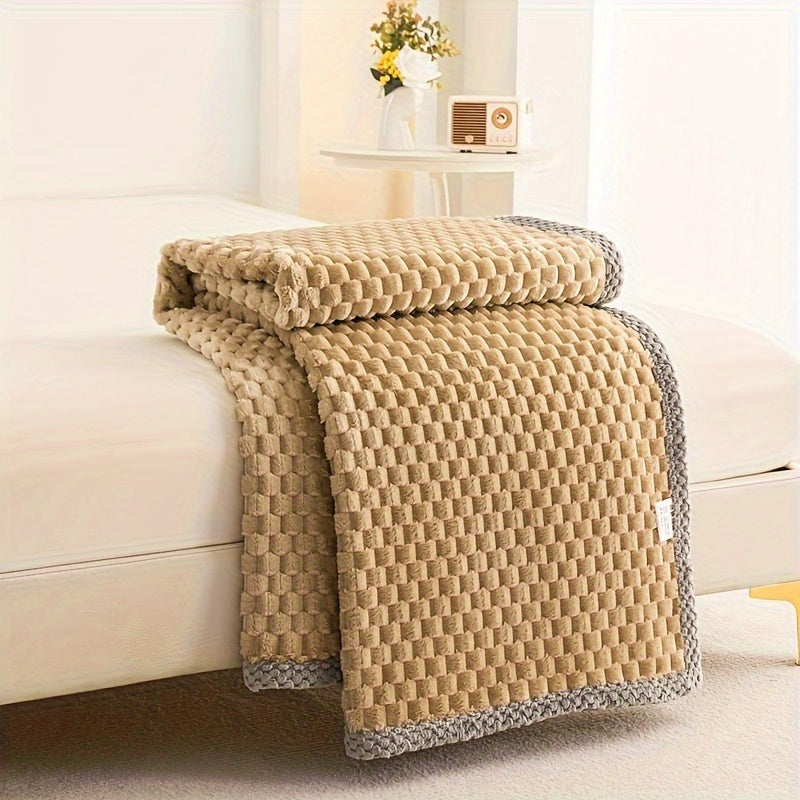 Fleece throw with a block texture and knitted trim draped over a bed - camel