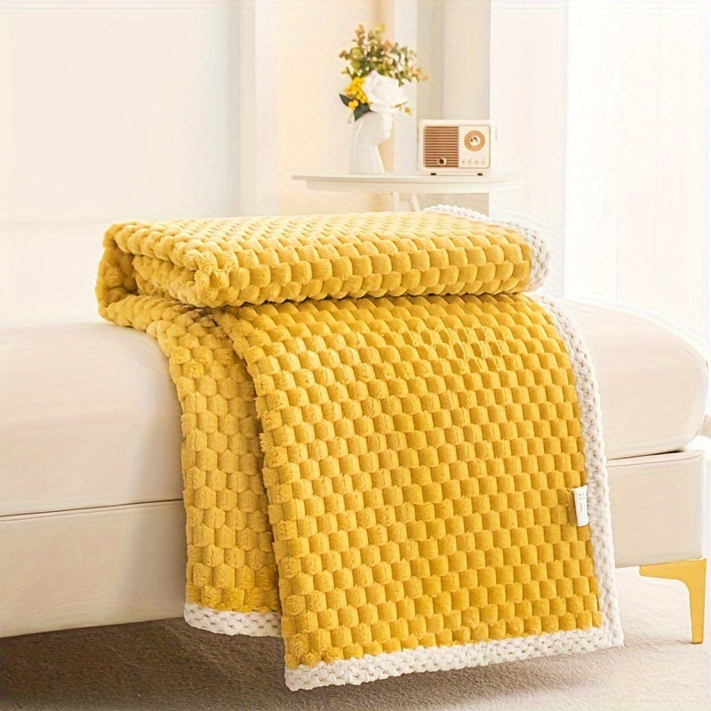 Fleece throw with a block texture and knitted trim draped over a bed - yellow