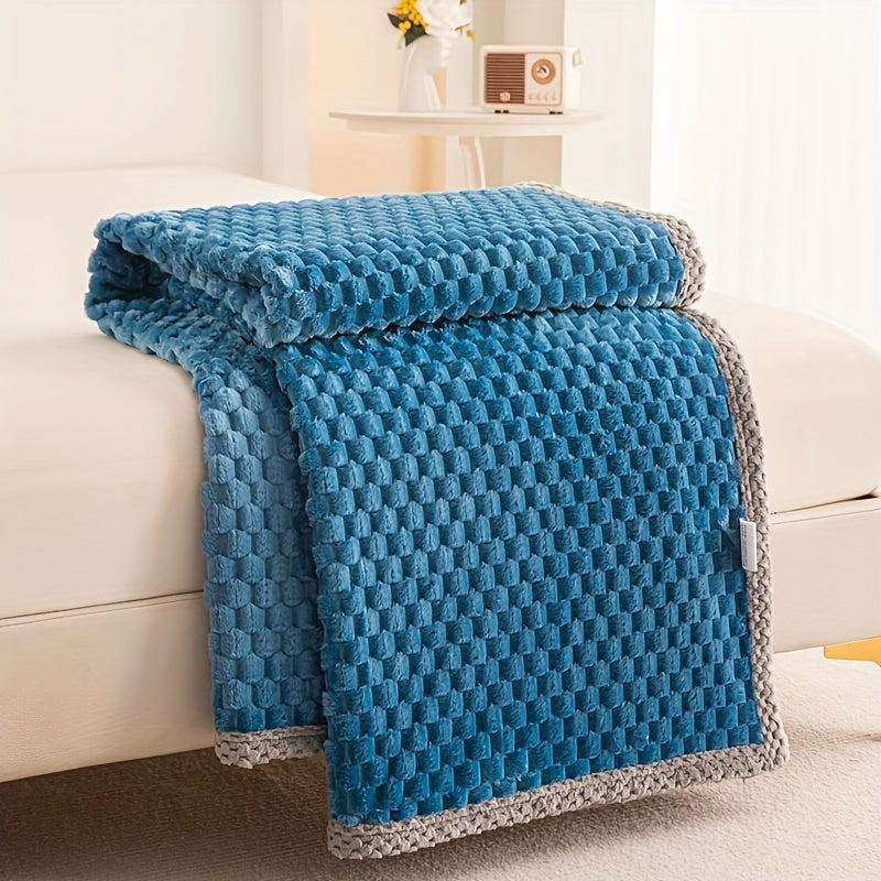 Fleece throw with a block texture and knitted trim draped over a bed - blue