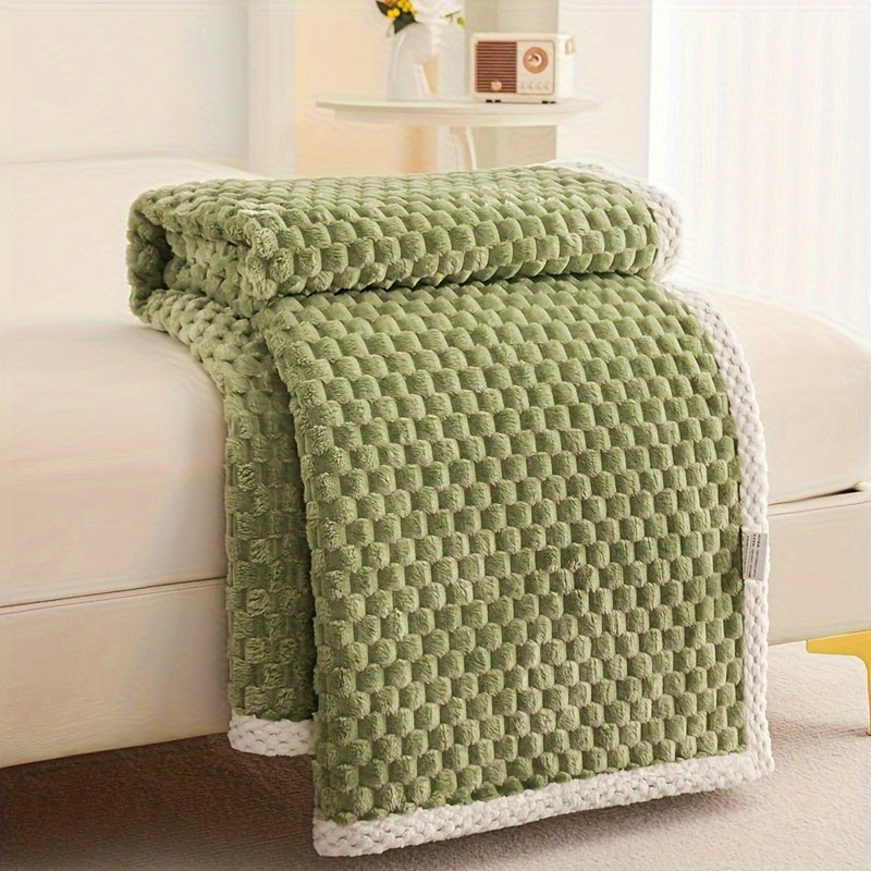 Fleece throw with a block texture and knitted trim draped over a bed - olive green
