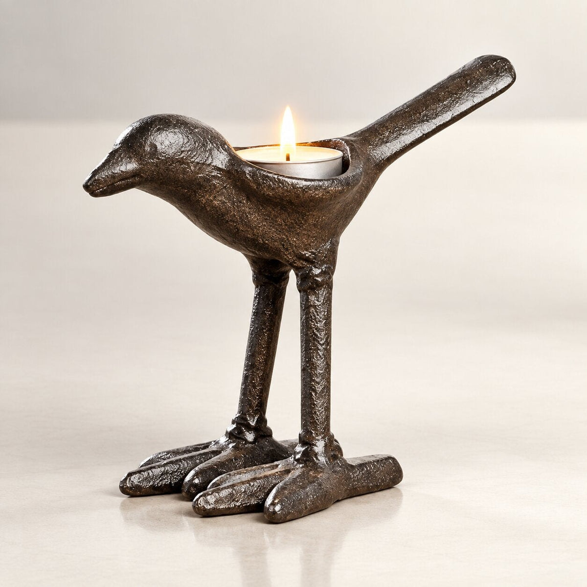 Dark iron tea light holder shaped like a bird with long legs