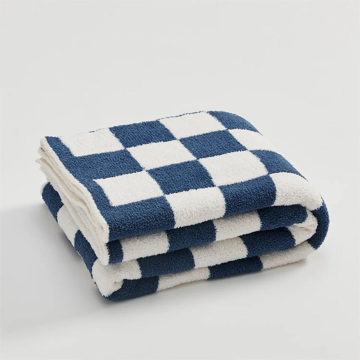 Knitted teddy throw with a checkerboard pattern over an armchair - navy