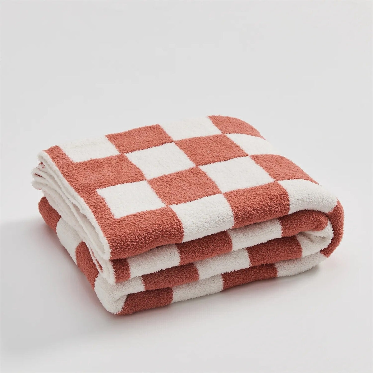 Knitted teddy throw with a checkerboard pattern over an armchair - coral red