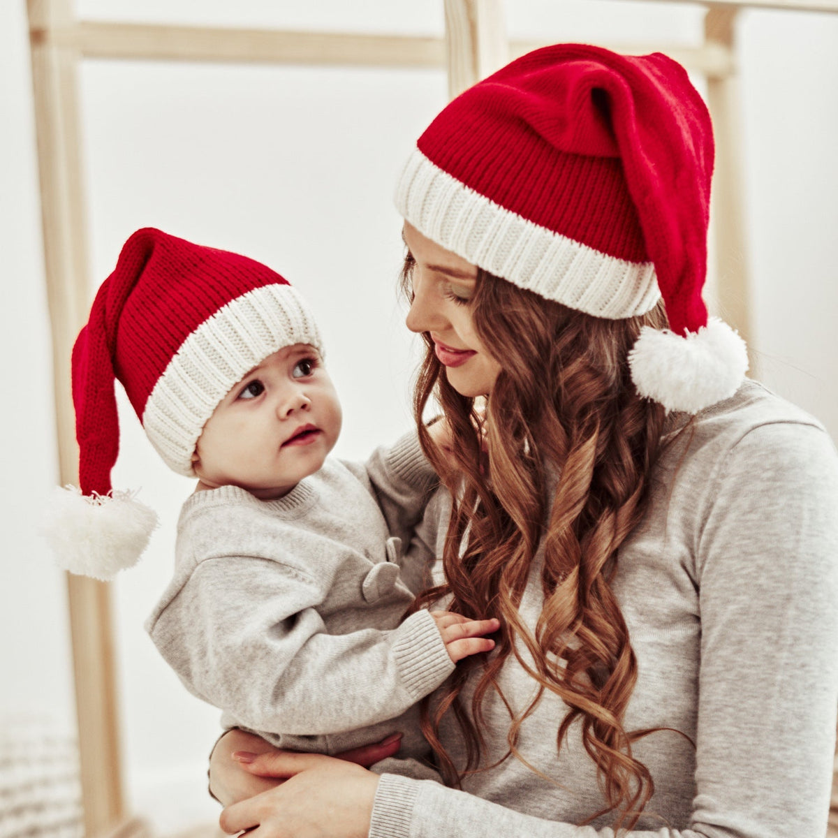 Red knitted Father Christmas hat with white cuff and pompom, parent and child