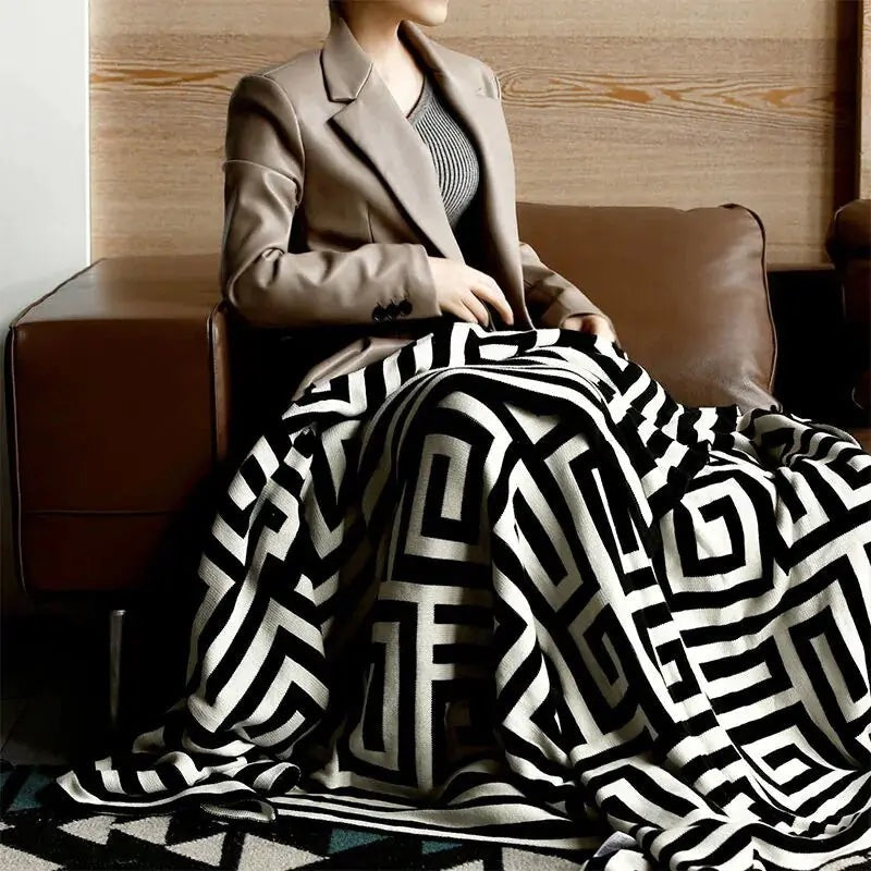 Knitted throw with a geometric pattern over a brown sofa - black