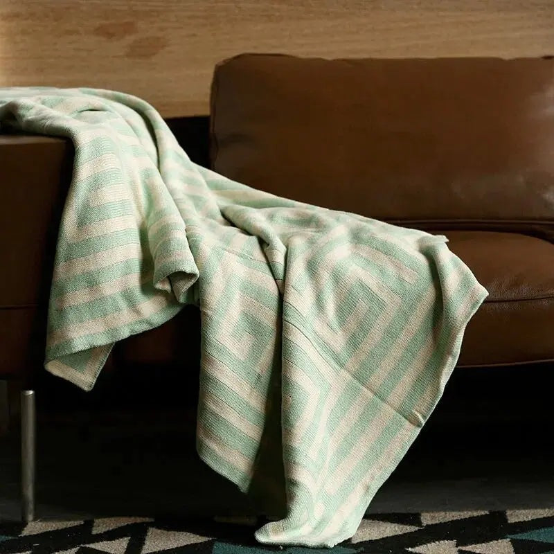 Knitted throw with a geometric pattern over a brown sofa - mint green