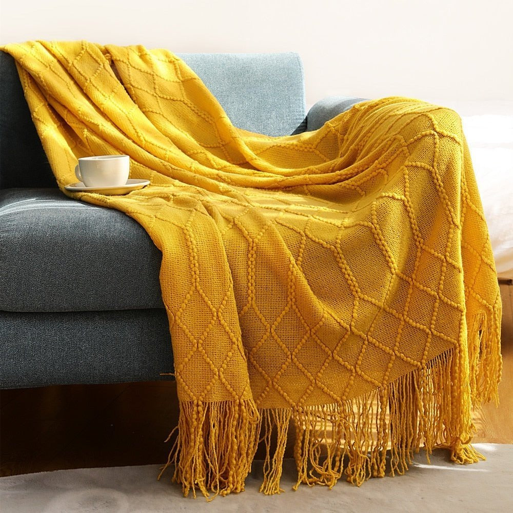 Knitted throw with a Scandinavian pattern and tassels over a chair - mustard