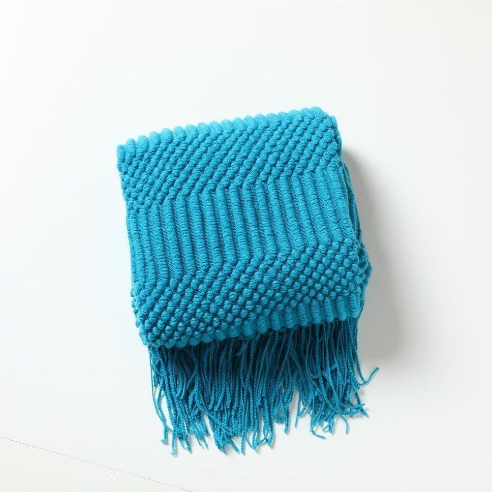 Knitted throw with a Scandinavian pattern and tassels over a chair - turquoise
