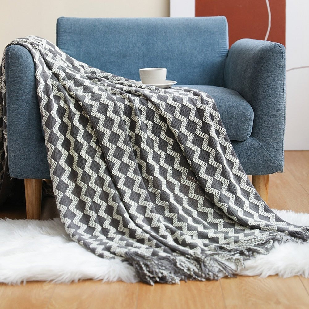 Knitted throw with a Scandinavian pattern and tassels over a chair - grey and white zigzag