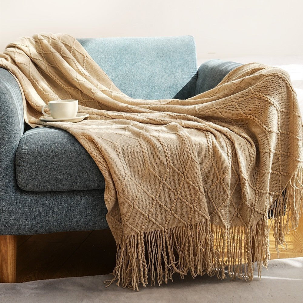 Knitted throw with a Scandinavian pattern and tassels over a chair - camel